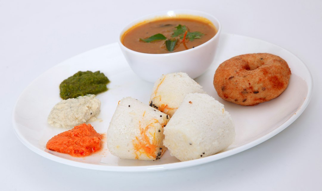Steamed idli served with sambar and coconut chutney, a classic South Indian breakfast dish