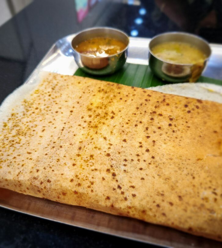 Traditional South Indian meal with folded dosa on a banana leaf tray, Indian restaurant Amsterdam